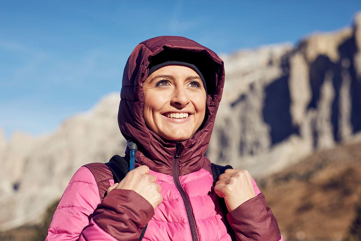 Female hiker or mountain guide with pink jacket in the mountains, with a water tube visible